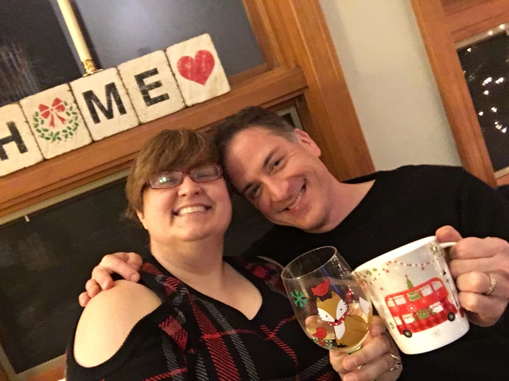 Picture of MezzoSherri and Mr. Mezzo, toasting the camera with a glass of wine (Sherri) and a mug of coca (Mr. Mezz)