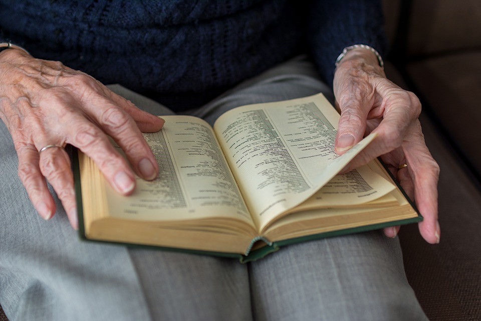 Close up image of an old woman's hands turning the pages of a book.