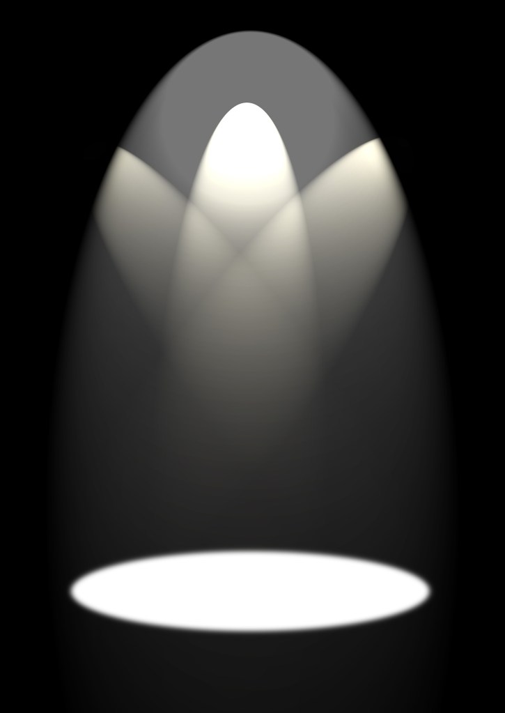 A black and white of three spotlight beams merging to form an illuminated circle on an empty stage.