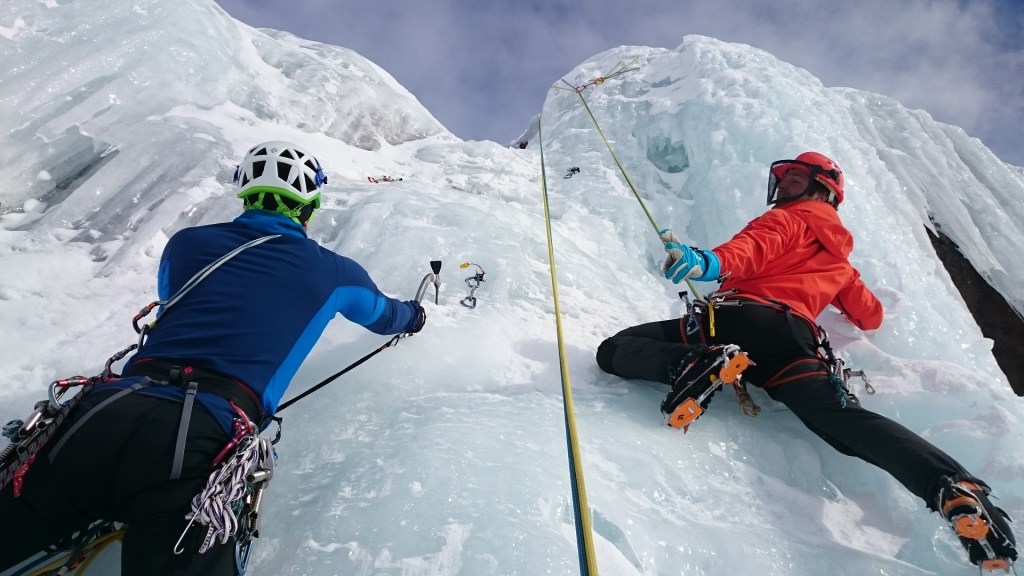 Two men climbing an ice-covered rock wall.