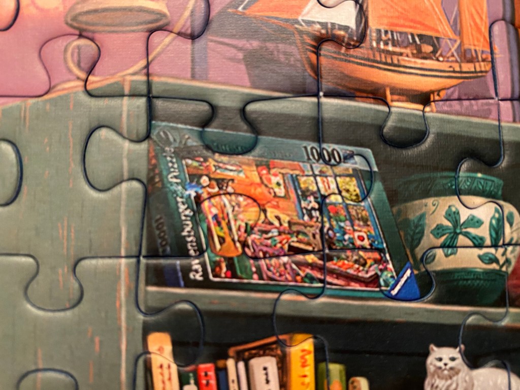 Close-up of a completed (Ravensburger) jigsaw puzzle, showing a Ravensburger jigsaw puzzle box on a bookshelf.