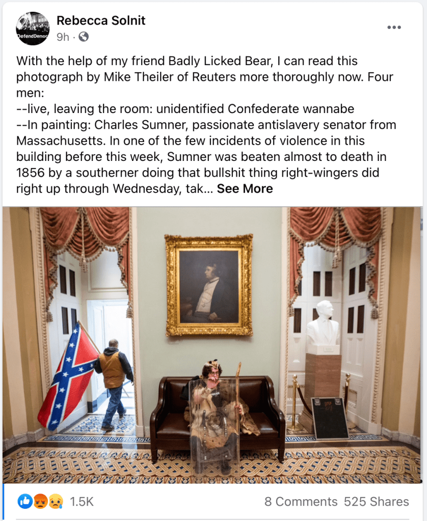 A screen shot of a Facebook post by Rebecca Solnit, interpreting a photograph showing an insurrectionist carrying a Confederate battle flag in a Capitol hallway while another rioter sits on a leather couch holding stolen riot police gear. (Link to full post in photo caption.)